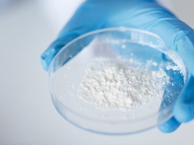 researcher holding a petri dish with titanium dioxide powder in it